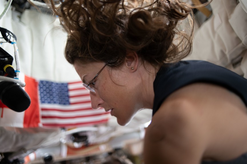 A woman in space exercises, with her long hair floating above her.