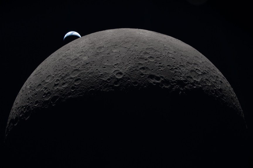 The moon as viewed from its dark side with the crescent of the Earth rising behind it.
