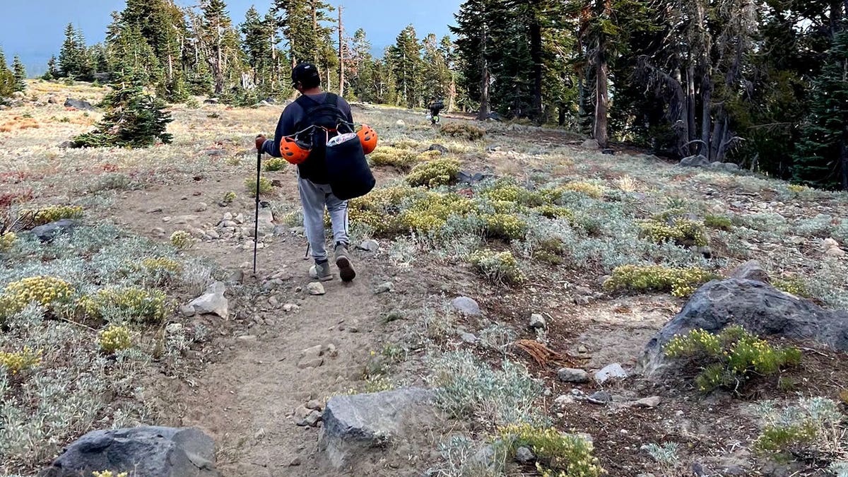 A rescuer hikes along rough terrain and rocks