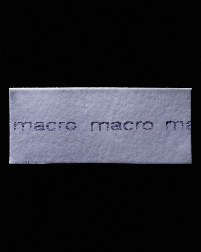 Paper against black backgrounds reads “macro macro ma”