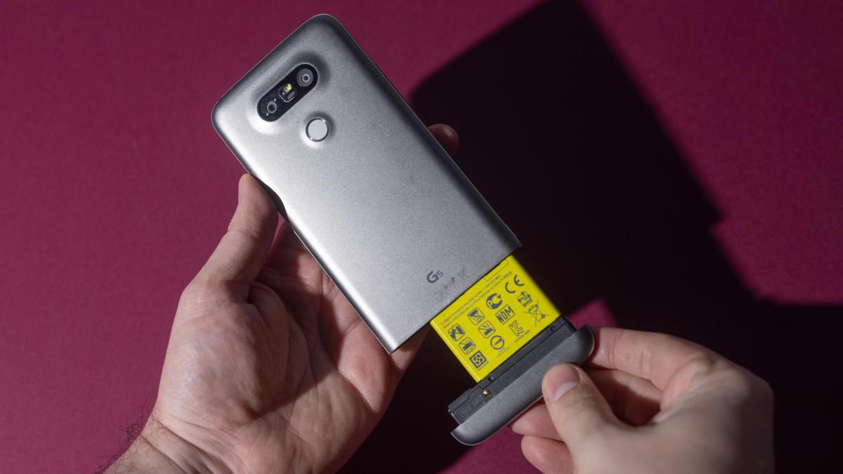 Hands holding the LG G5, which has a slide-out battery