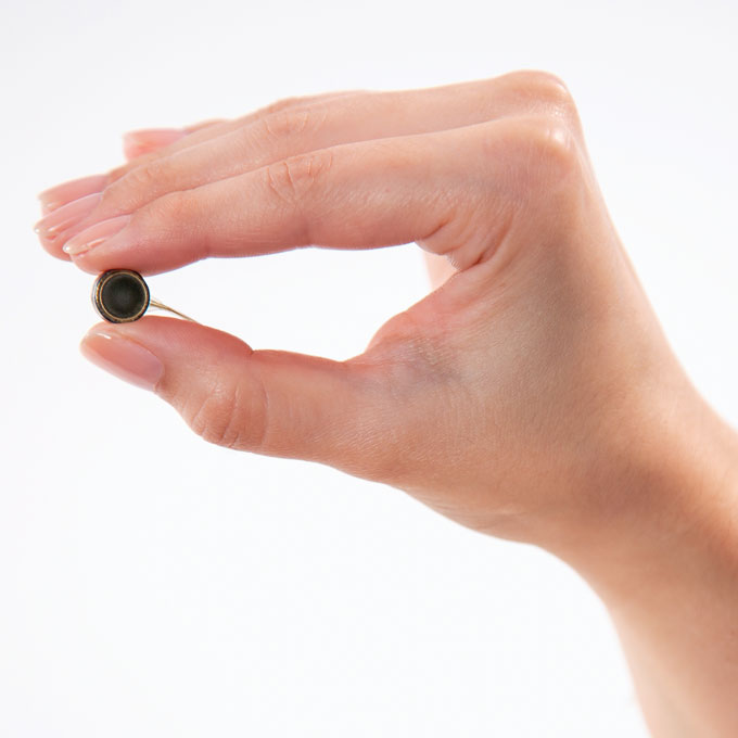 A photo of a hand holding a dime-sized brain implant