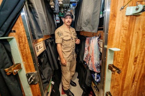 A crew member stands in a nine-person sleeping quarters on the USS Colorado. 