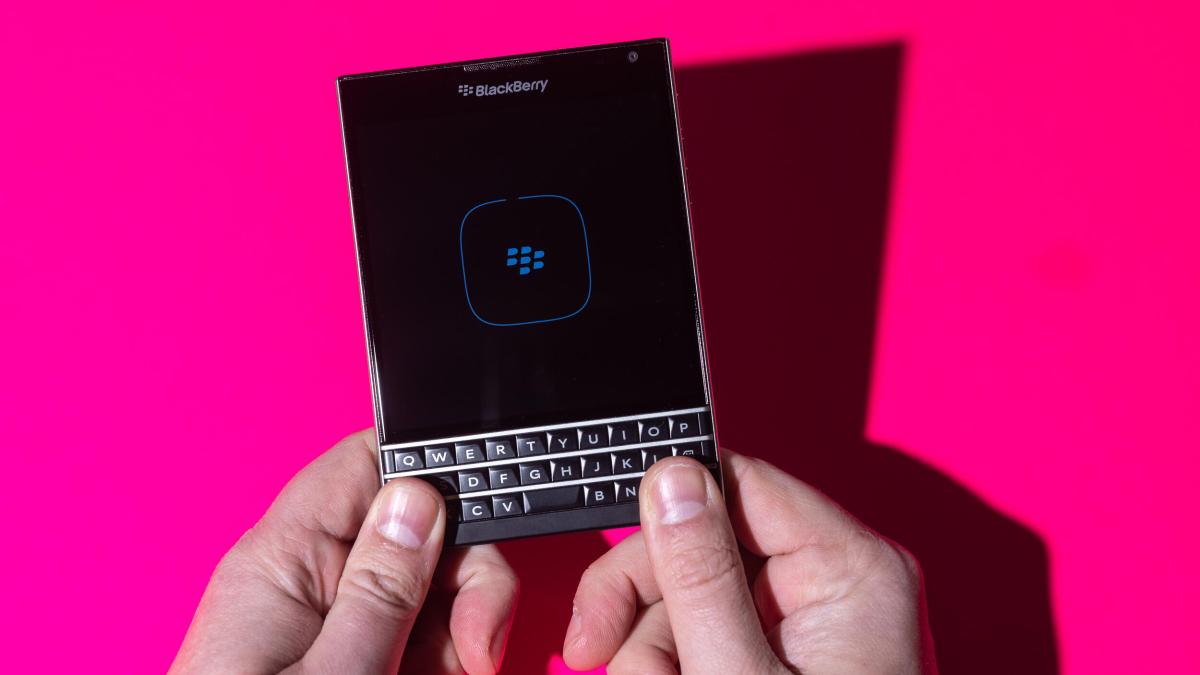 Hands holding a square Blackberry Passport phone