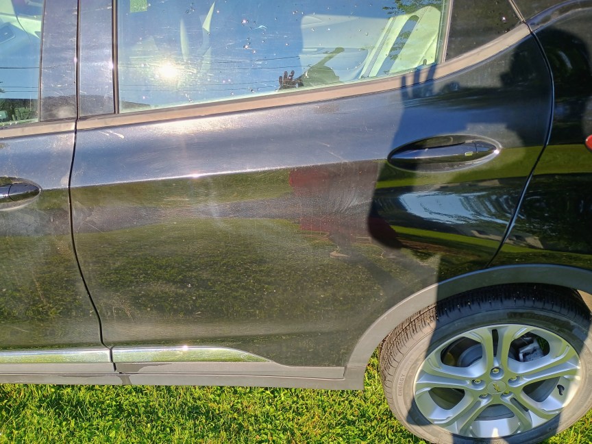 The rear driver-side door of a black car after being washed with the LawnMaster LT506-2000A. It still has some visible muddy spots, but is otherwise pretty clean.