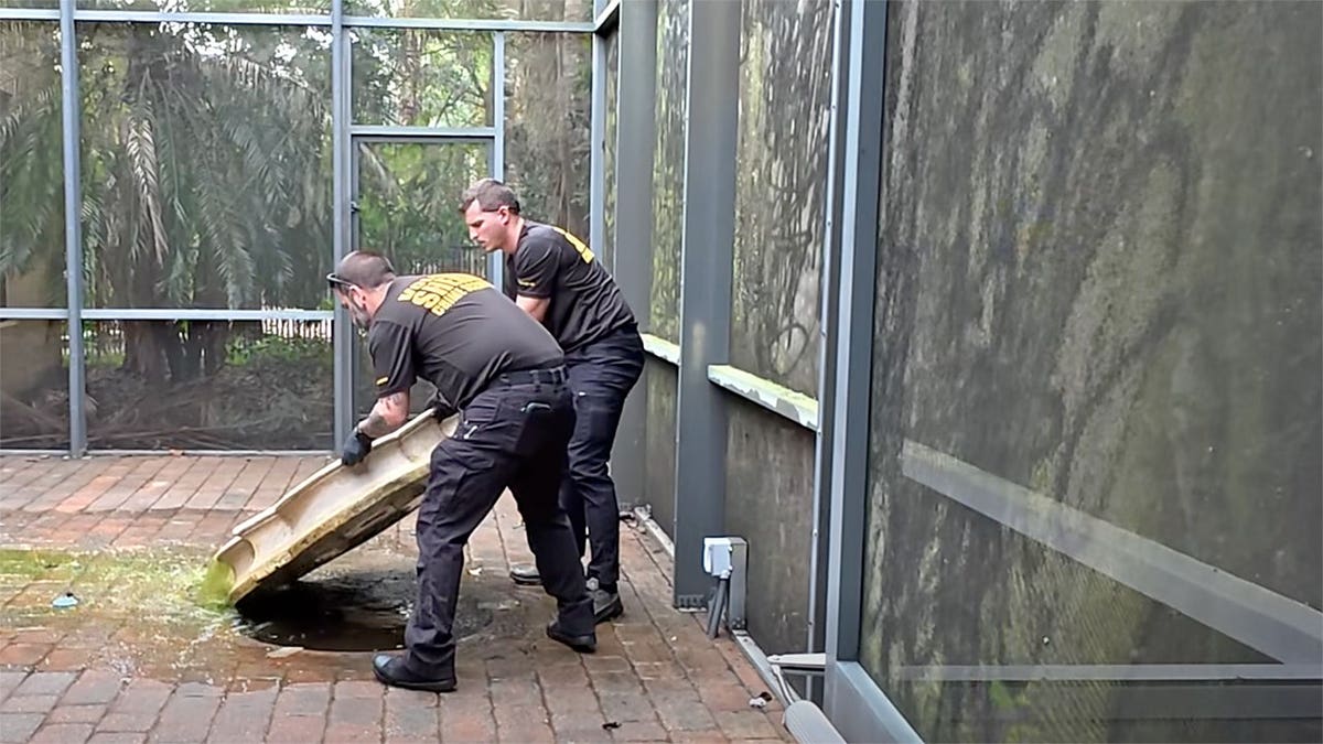 Volusia County investigators lift a large structure while searching a property in DeBary, Florida.