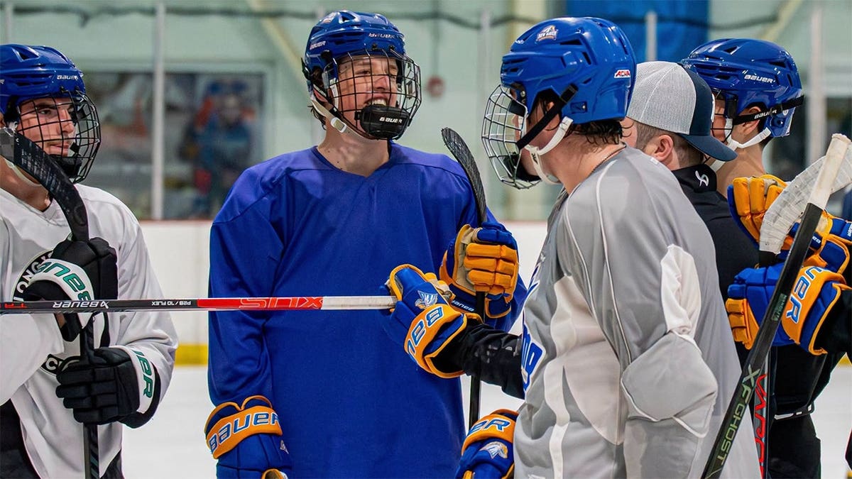 University of New Haven hockey captain Ryan O'Shea stands on the ice with teammates.