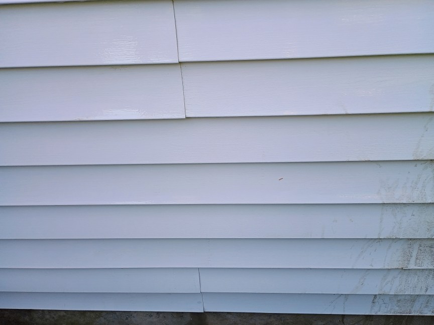 A view of house siding after it was cleaned with a LawnMaster pressure washer. The result looks very clean.