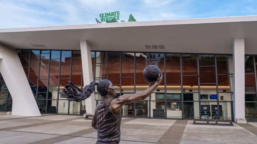 Exterior of a sports arena with a bronze statue of a woman playing basketball.