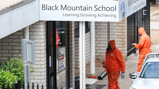 People in hazmat suits at Black Mountain School with some schools in Canberra closed due to potential asbestos contamination.