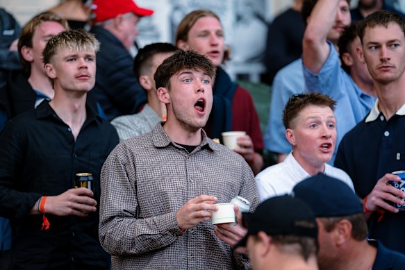 Spectators watch on as the greyhounds race.