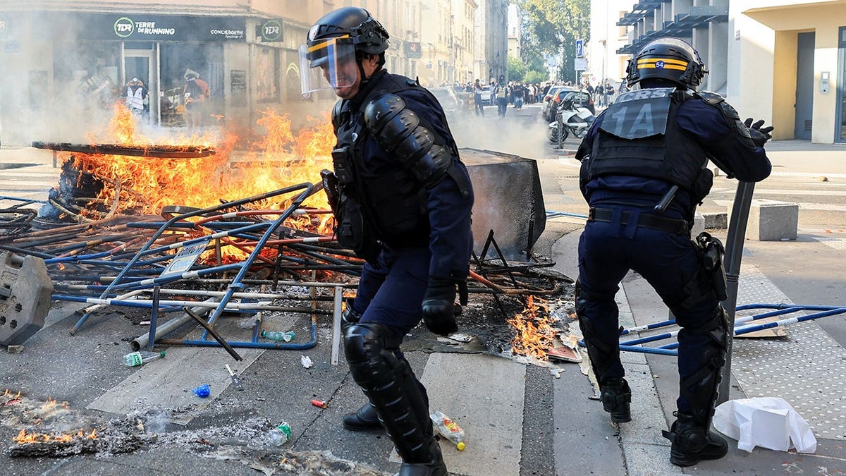 French riot police officers remove a burning street barricade during a student demonstration in Lyon.