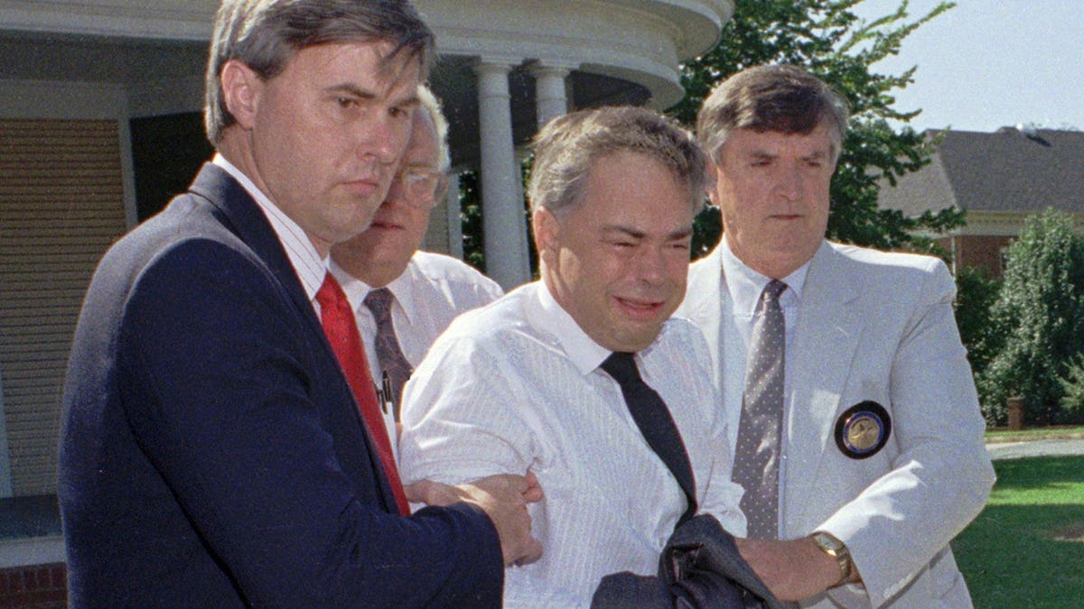 Jim Bakker is escorted by U.S. marshals from an office in Charlotte, N.C.