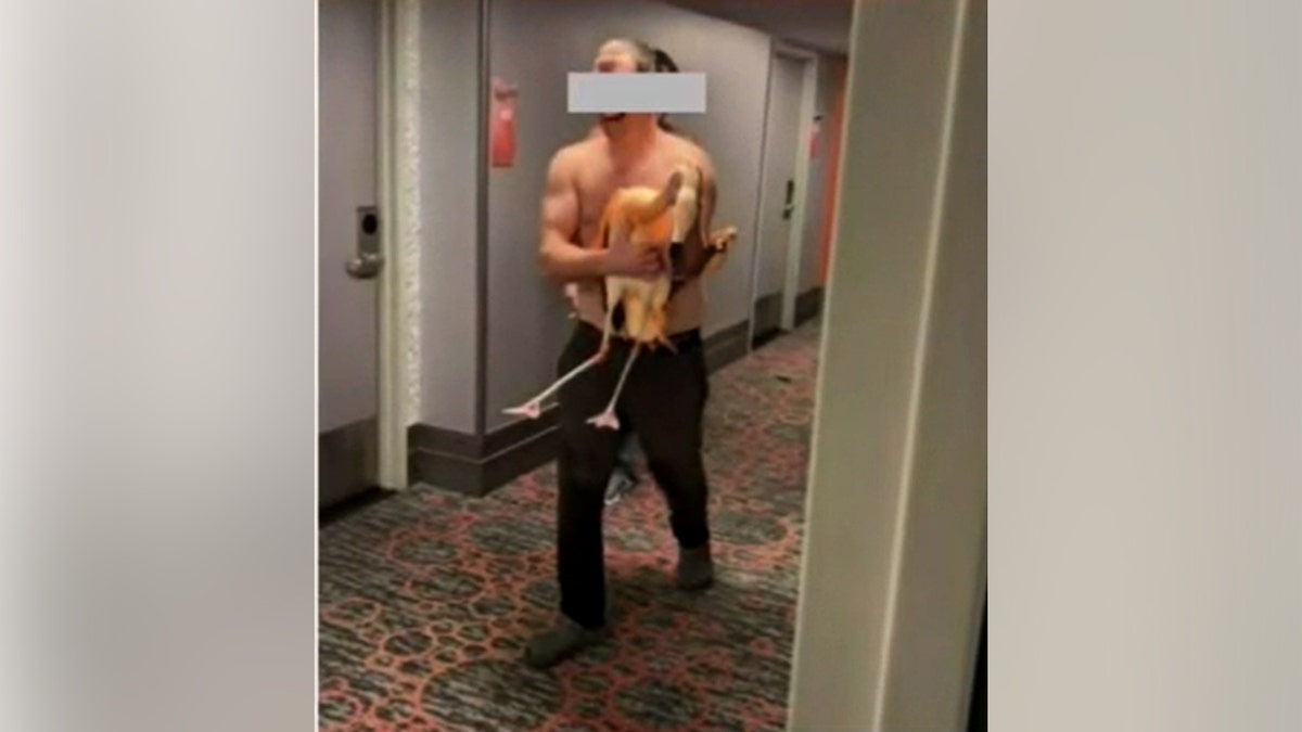 A man holding a flamingo in a hallway