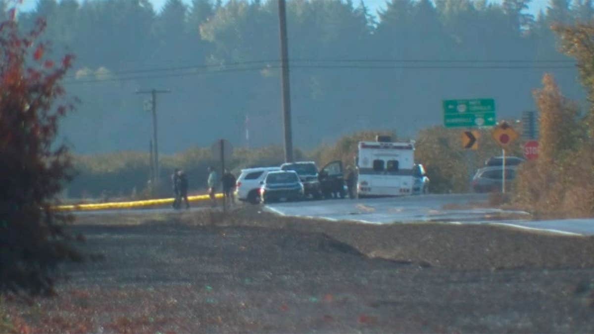 Emergency vehicles and personnel near a closed Oregon road following a helicopter collision