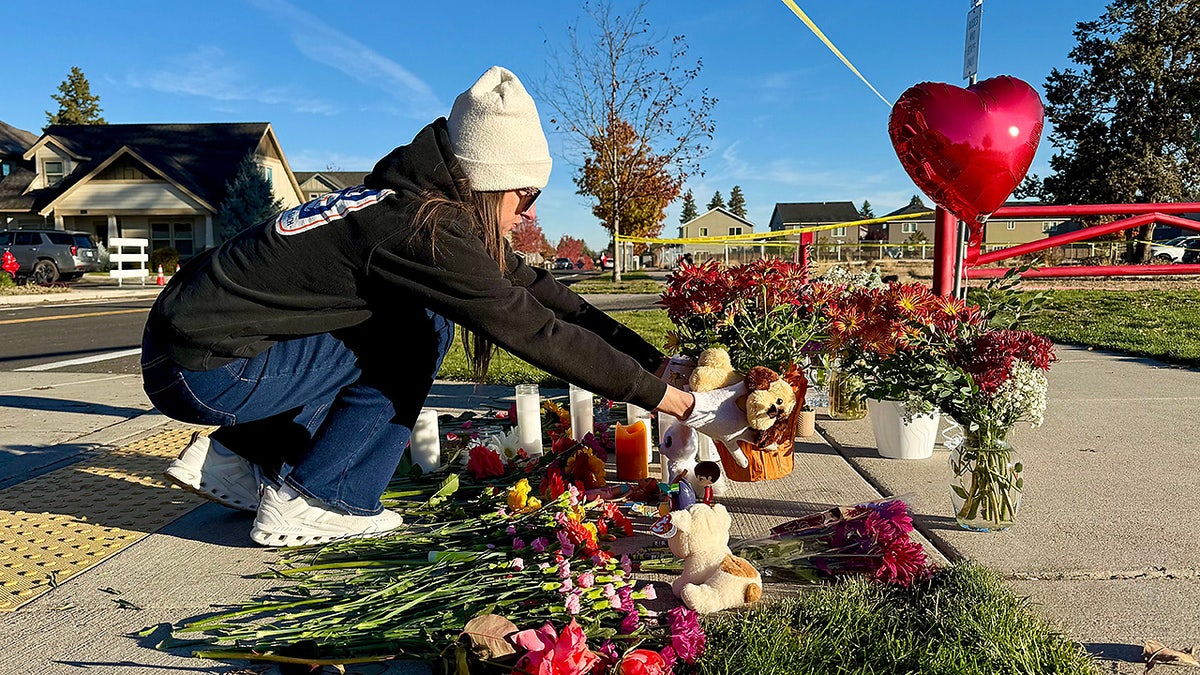 A person places flowers at a makeshift memorial on the other side of Silver Rail Elementary School in Bend, Ore., on Friday, Oct. 16, 2026, a day after a deadly shooting.