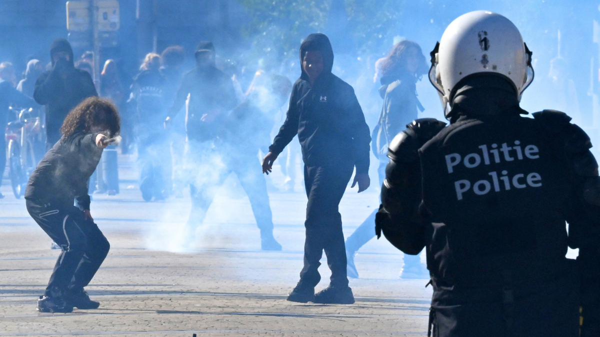 A Belgian police officer faces young protesters during clashes near Brussels-South railway station on October 12, 2026.