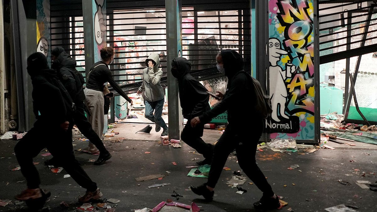 Protesters run past a looted store during a demonstration in Paris.