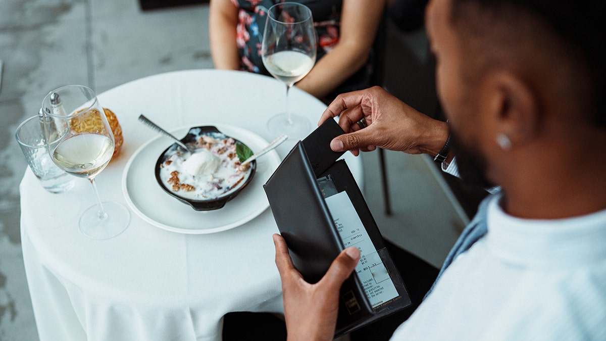 Man pays dinner bill with credit card.